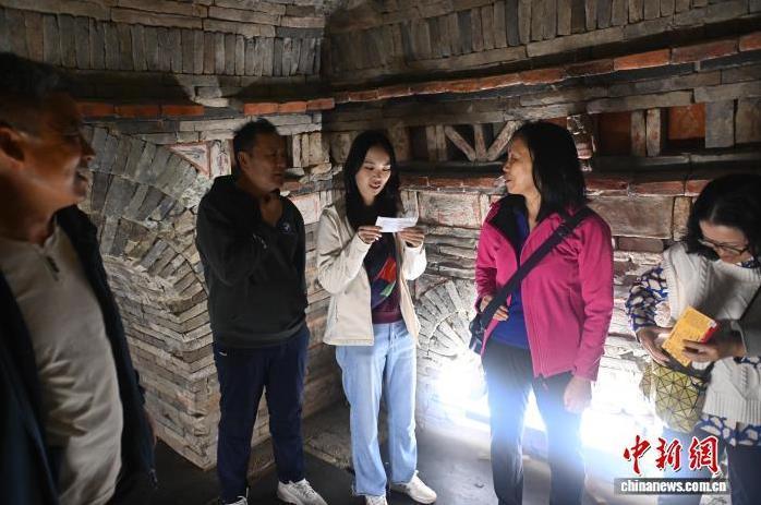 9月24日,在位于甘肃省嘉峪关市的嘉峪关新城魏晋墓群六号墓内,游客对照了解画像砖里的故事。中新社记者 李亚龙 摄