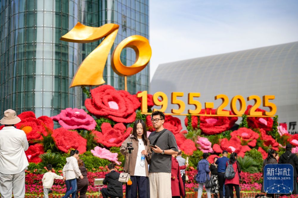 ↑ 10月1日,游客在新疆乌鲁木齐文化中心庆祝新疆维吾尔自治区成立70周年景观前拍照留念。新华社记者 徐宏岩 摄