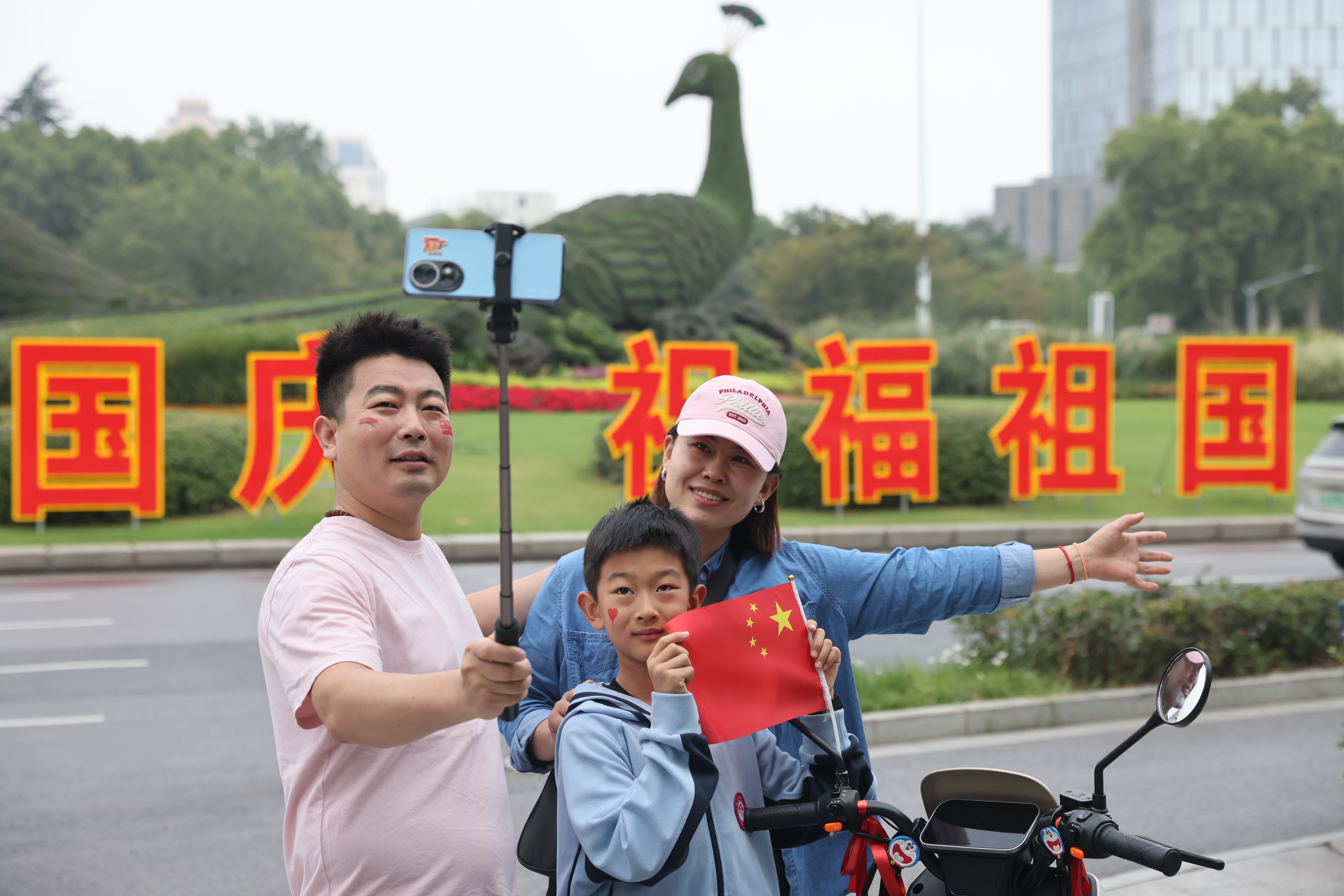 鼓楼广场国庆标语前，市民刘先生一家三口合影留念，为祖国庆生。崔晓 戚珂嘉 摄