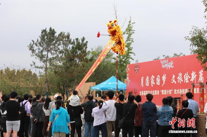 国庆期间，河北省沧州铁狮与旧城遗址公园热闹非凡。铁狮子脚下，舞龙、舞狮等民俗表演精彩纷呈，非遗展示展演尽显地方特色。沧州是一座历史名城，又被称为“狮城”。图为10月2日，游客在河北省沧州铁狮与旧城遗址公园观看非遗舞狮表演。田博 摄