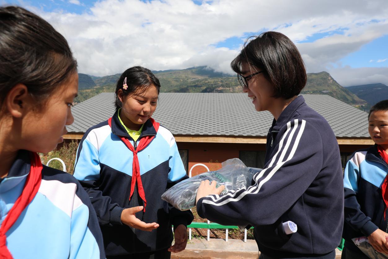 北仑区慈善总会工作人员为美姑县荞麦花开儿童之家的学生发放运动服