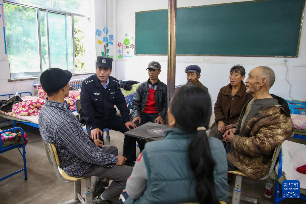 9月28日，在定西市漳县木林小学安置点宿舍内，公安民警与受灾群众交流。
