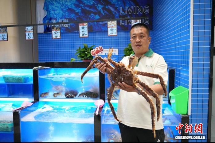 交投万链环球生鲜产品直营店工作人员向顾客展示一只鲜活的帝王蟹。俱凝搏 摄