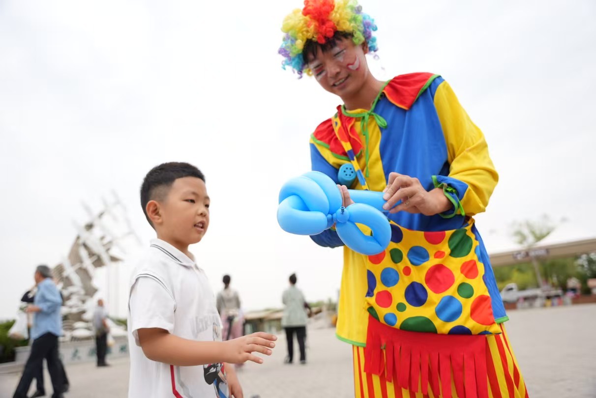 小丑演员给游客制作气球礼物。刘晓天 摄