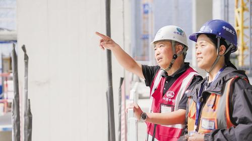 10月1日，在雄安新区财富大厦项目现场，工地“夫妻档”梁俊岭（左）和李随连（右）在讨论项目建设情况。本报见习记者 李 畅摄