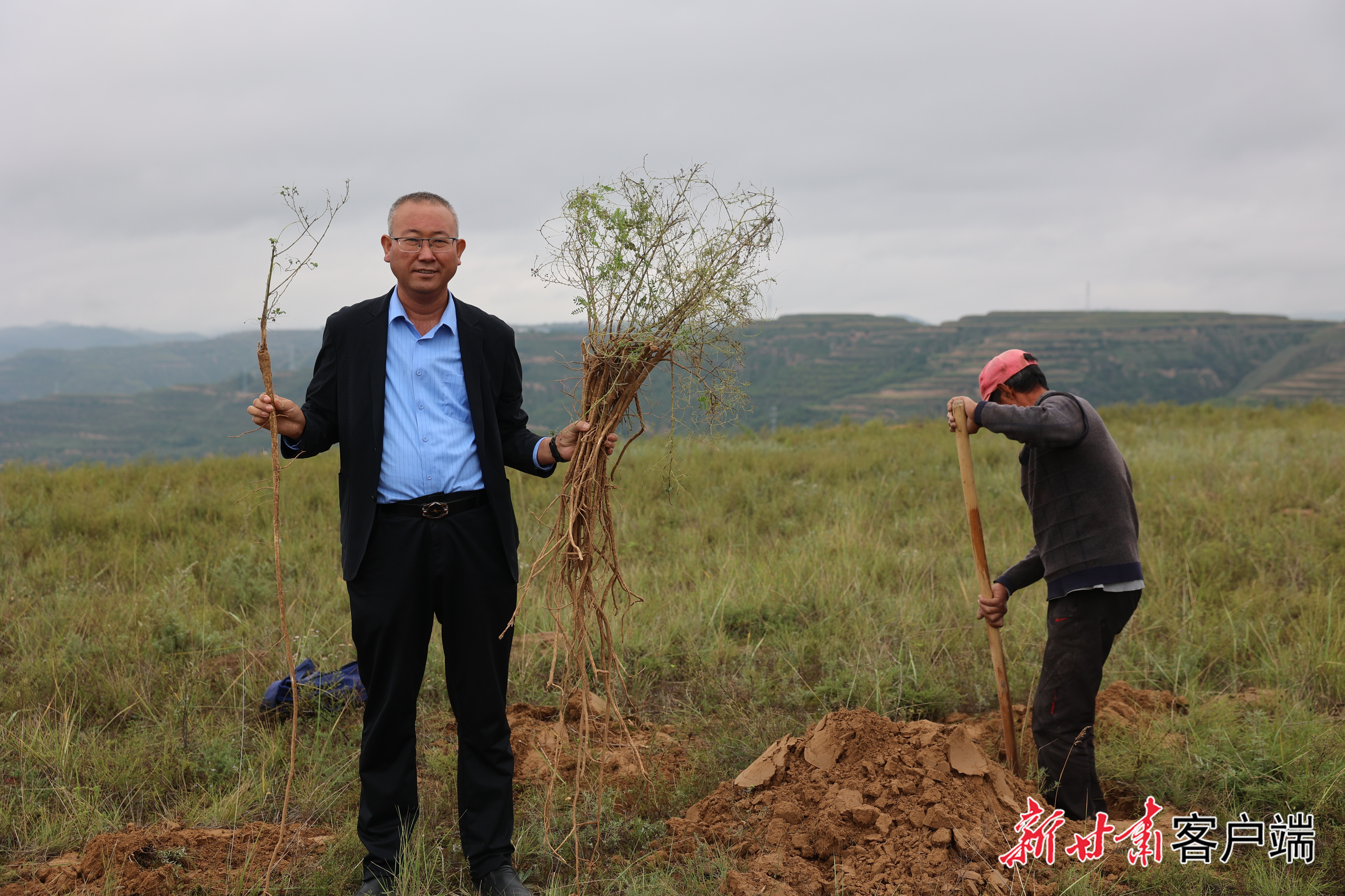2025年“全国十佳农民”姚文智(左)在地头查看中药材长势