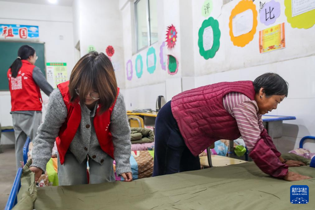 9月28日，在定西市漳县木林小学安置点宿舍内，志愿者帮助受灾群众铺床。