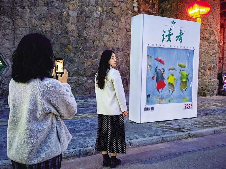 在《读者》杂志牌前打个卡　记者　高宏梅　摄