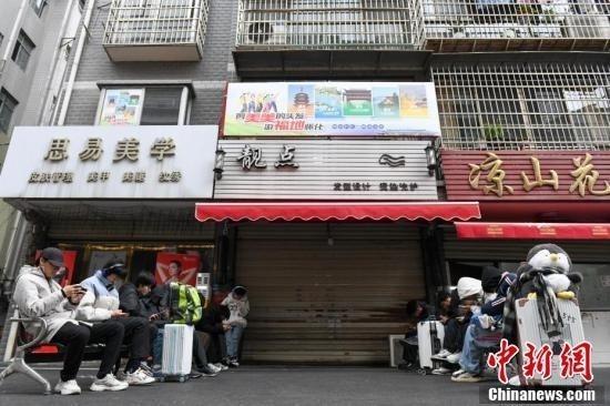 2025年1月8日，眾多外地顧客提著行李箱等待李曉華的理發店開門。中新社記者 楊華峰 攝