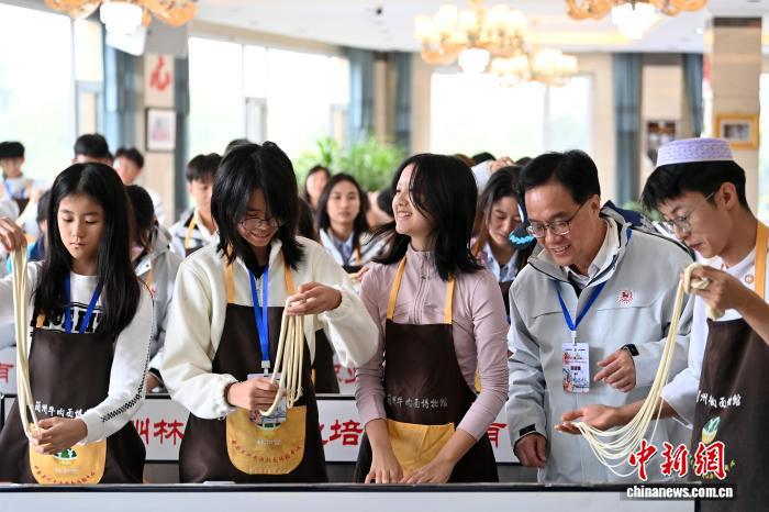 10月10日，“大手牵小手·丝路一起走”第三届澳门青少年国情研学活动开班仪式在甘肃兰州举行。此次活动为期7天，来自澳门7所学校的20余名青少年将沿着古丝绸之路，走进兰州、平凉、庆阳等地，感悟甘肃深厚的历史文化底蕴。图为澳门青少年在兰州牛肉面博物馆体验牛肉面文化。中新社记者　九美旦增　摄