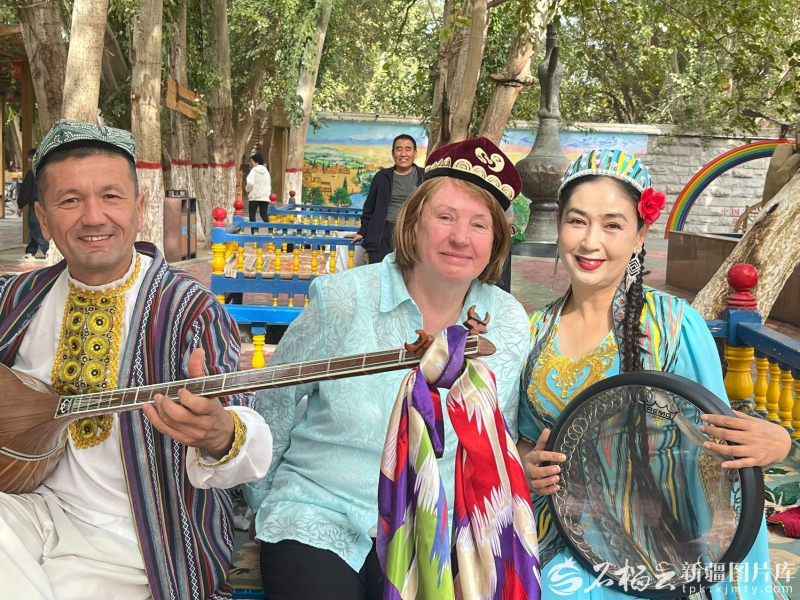 澳大利亚80岁游客麦迪娜(中)在景区与艺人们合照。祖力菲亚·艾买提摄