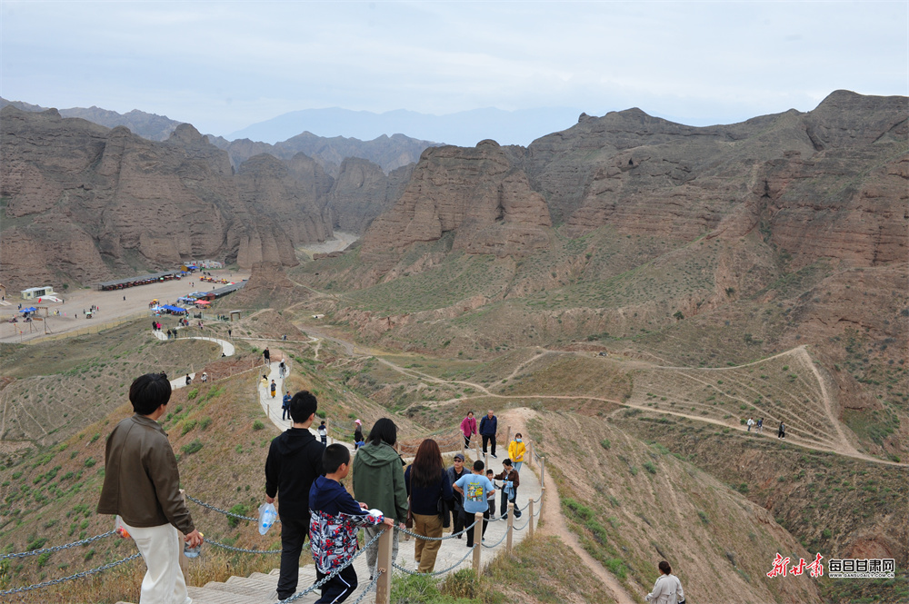 国庆中秋假期，景泰黄河石林景区内，游客们沿着饮马沟大峡谷蜿蜒曲折的步道深入其中，欣赏崖壁陡峭、谷底深邃的奇特地貌景观，一座座石柱形态各异，如刀劈斧削或神兽盘踞。新甘肃·每日甘肃网通讯员　寇明灿　摄影报道