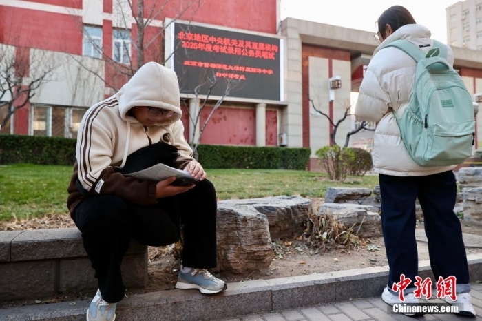 资料图：2024年12月1日，北京首都师范大学附属丽泽中学初中部考点外，考生抓紧时间复习。当日，中央机关及其直属机构2025年度考试录用公务员公共科目笔试举行。中新社记者 易海菲 摄