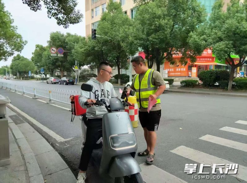 街道上,“两站两员”与交警一同上路,对未按规定佩戴头盔的摩托车骑乘人员进行现场劝导和教育。 长沙晚报通讯员 赵东平 摄
