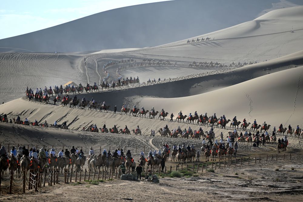 2025年8月9日，游客在甘肃省敦煌市鸣沙山月牙泉景区游览。新华社发（张晓亮　摄）