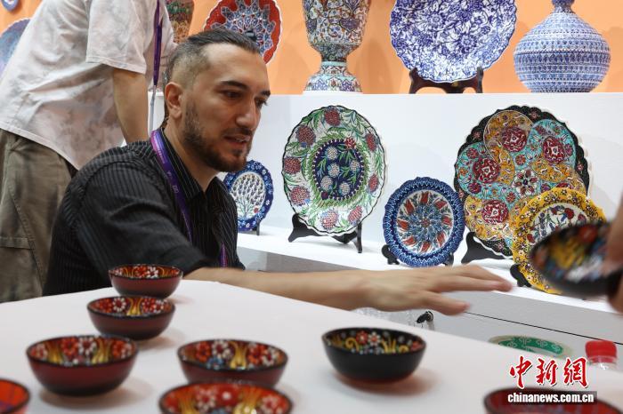 图为来自土耳其的参展商巴特正在为参观者介绍现场展销的传统手工瓷器。中新社记者 刘占昆 摄
