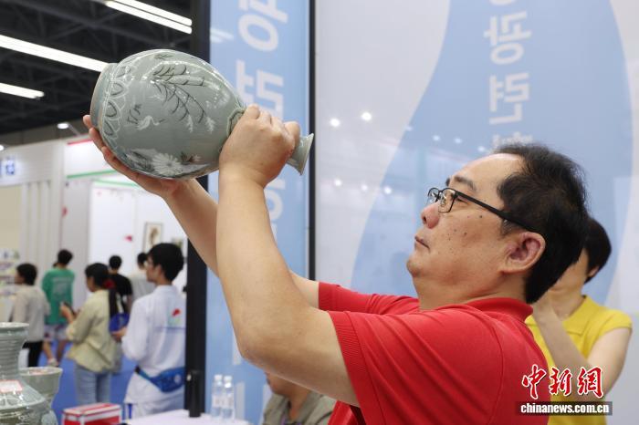 图为参观者正在端详现场展销的朝鲜高丽青瓷。中新社记者 刘占昆 摄