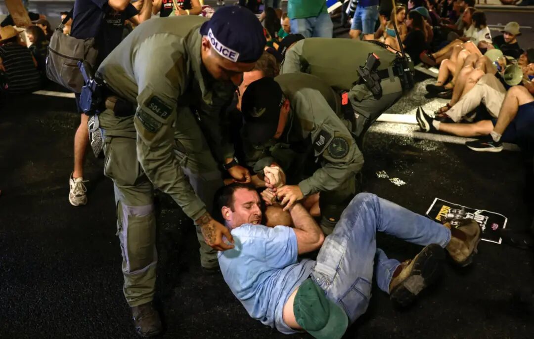 以色列警员在耶路撒月的一次反内塔尼亚胡政府抗议活动中,将一名堵塞交通的示威者强制移开。(图源:纽约时报)