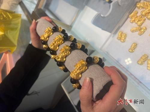 销售员取出黄金貔貅手链供顾客挑选。
