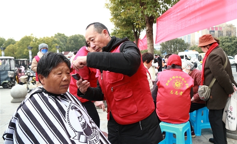 驿城区爱心志愿者走上街头为市民免费理发。