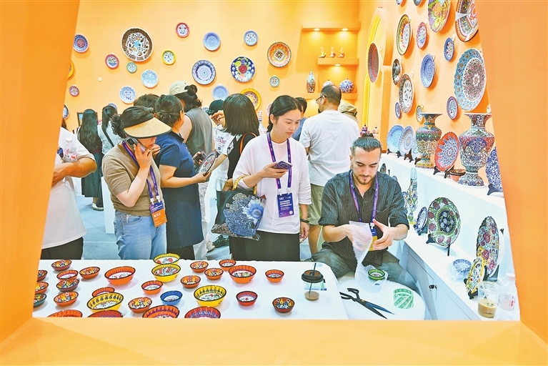 10月18日，土耳其参展商巴特（右）携传统手工瓷器亮相2025中国景德镇国际陶瓷博览会，精美的作品吸引众多游客驻足观赏。