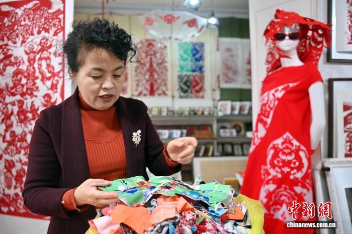 10月24日,在甘肃庆阳市西峰区锦绣坊,民间手艺人张锐利从生活中汲取灵感,用一双巧手将边角碎布变废为宝创作布贴画。布贴画源于陇东地区妇女缝补衣物的智慧,以碎布为料,经剪拼贴缝成画。2024年12月,庆阳民间布贴画艺术被列入甘肃省第五批省级非物质文化遗产代表性项目名录。图为张锐利挑选创作布贴画所需布料。中新社记者 九美旦增 摄