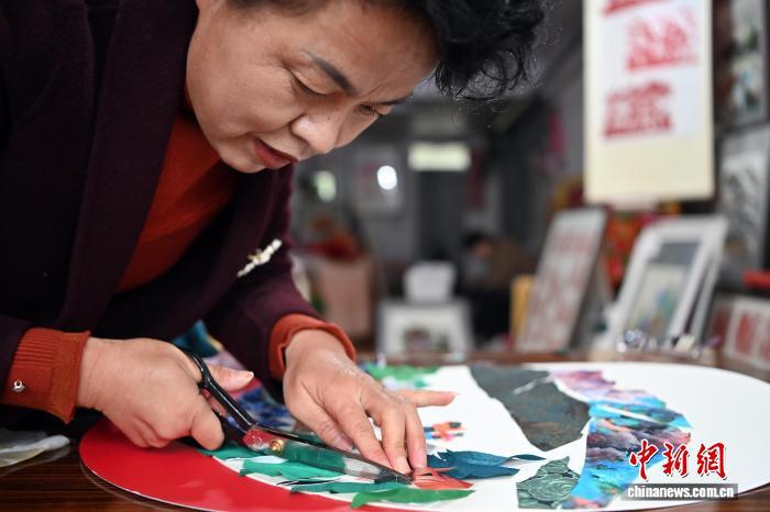 10月24日,在甘肃庆阳市西峰区锦绣坊,民间手艺人张锐利从生活中汲取灵感,用一双巧手将边角碎布变废为宝创作布贴画。布贴画源于陇东地区妇女缝补衣物的智慧,以碎布为料,经剪拼贴缝成画。2024年12月,庆阳民间布贴画艺术被列入甘肃省第五批省级非物质文化遗产代表性项目名录。图为张锐利正在创作布贴画。中新社记者 九美旦增 摄