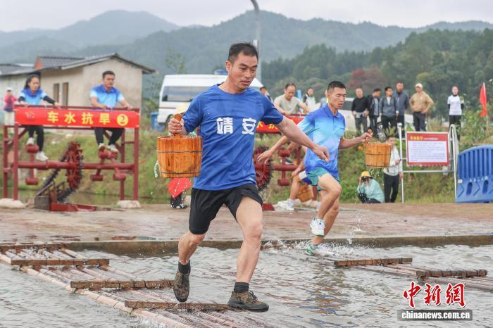 图为车水抗旱项目中,选手提桶通过放置在水面上的竹排。中新社记者 刘力鑫 摄
