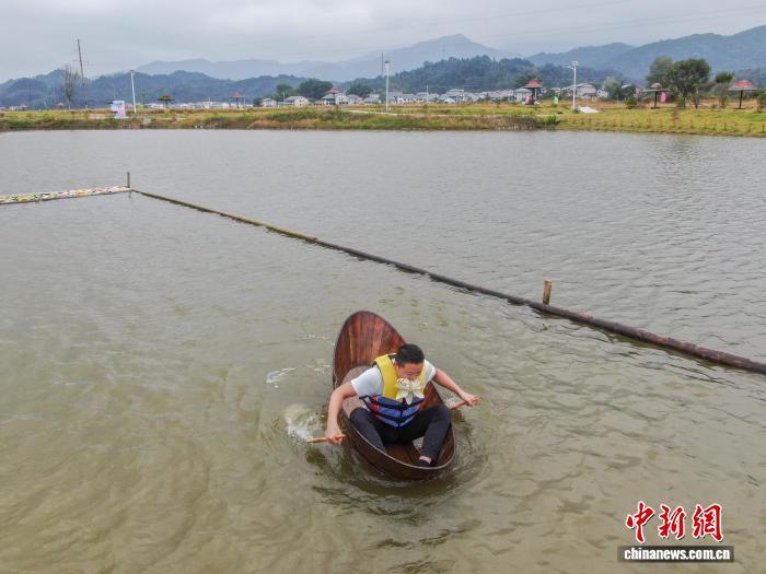 图为荷塘采莲项目中,一位选手用嘴衔着莲花道具往岸边划。(无人机照片)中新社记者 刘力鑫 摄