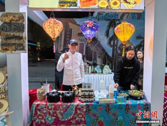 邓保罗(左一)在自己的摊位上推广南洋特色美食。 中新网记者 钟升 摄