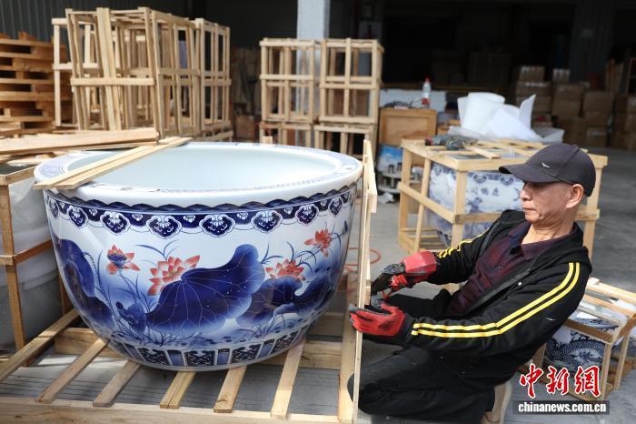 图为一家物流企业工作人员正在用木架为一大型陶瓷水缸进行打包。中新社记者 刘占昆 摄