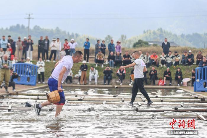 图为车水抗旱项目中,选手提桶通过放置在水面上的竹排。中新社记者 刘力鑫 摄