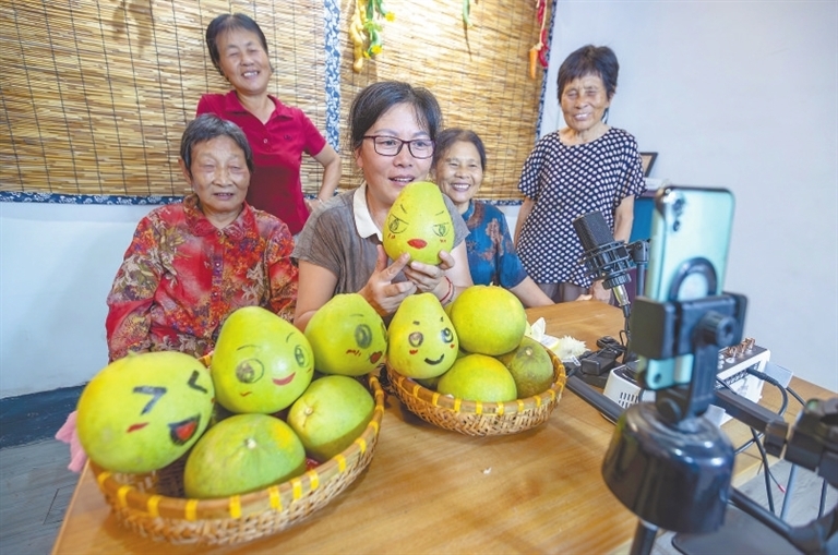 谢爱莲（中）带着“庙口妈妈”们直播推介家乡的井冈蜜柚。