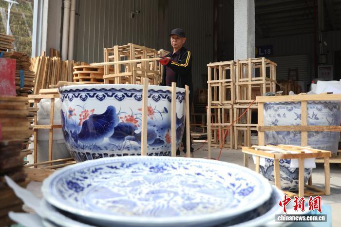 图为一家物流企业工作人员正在用木架为一大型陶瓷水缸进行打包。中新社记者 刘占昆 摄