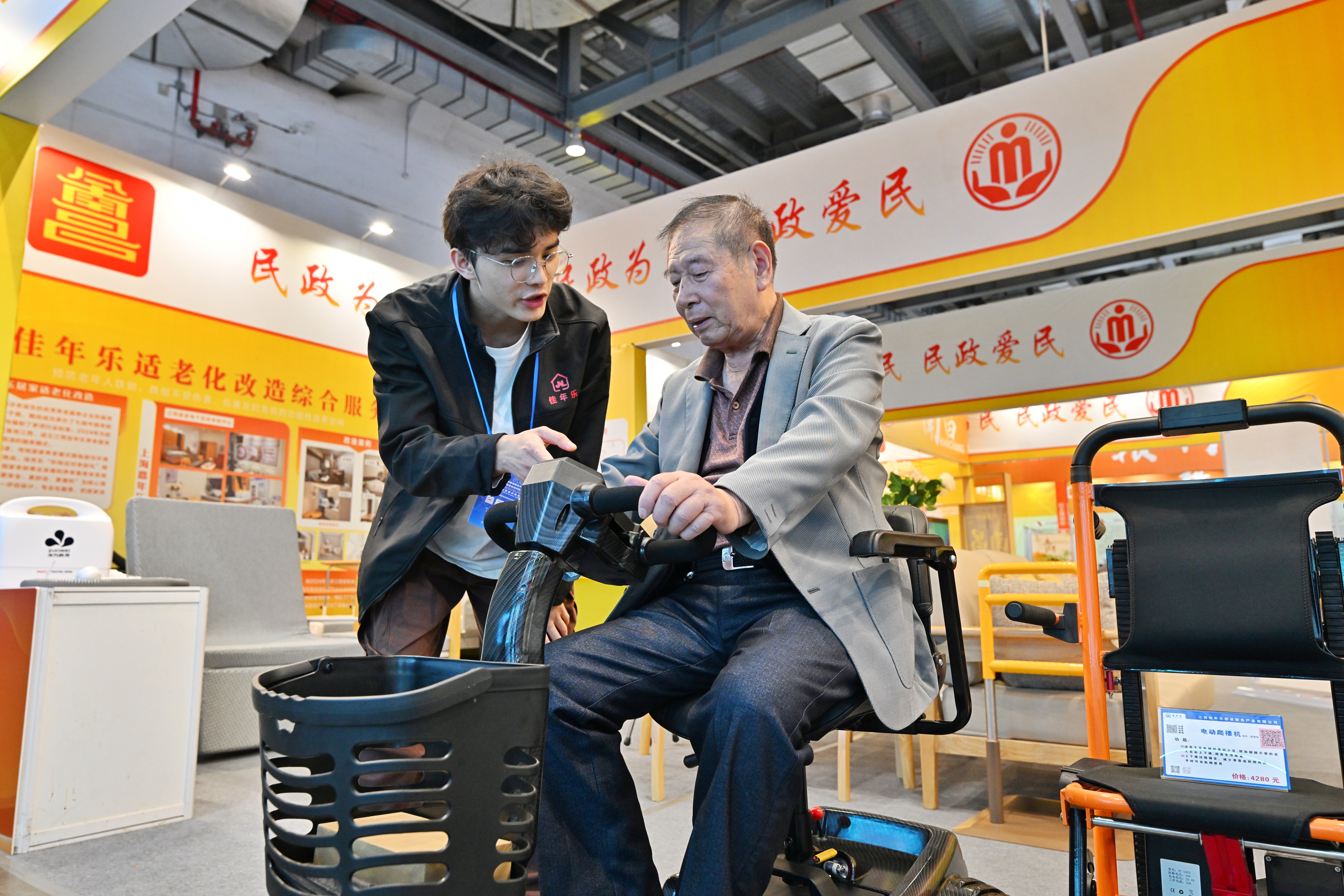 ▲一名78岁的老人（右）前来体验购买自动代步车。