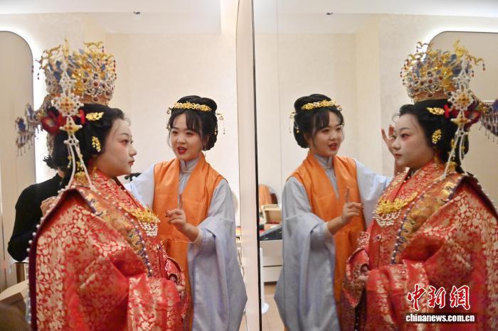 11月9日，吉林长春，任鸿洋(右)在为新妇整理婚服。中新社记者 张瑶 摄