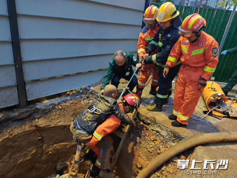 消防员从浑浊泥水中背出伤者。