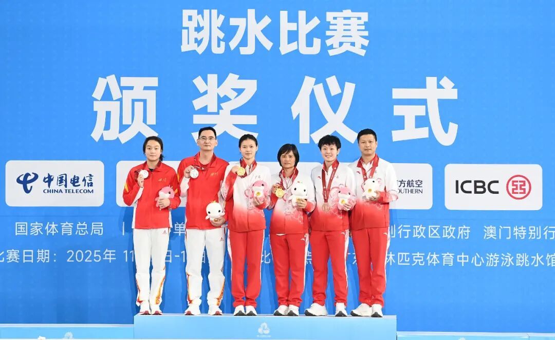 11月11日,第十五届全国运动会跳水项目女子3米跳板决赛在广州举行。冠军广东队选手林珊(左三),亚军四川队选手陈佳(左一)和季军广东队选手陈艺文(右二)以及教练员在领奖台上合影。