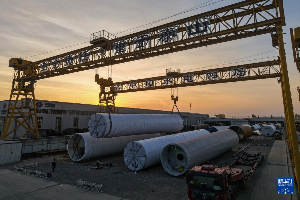 11月20日，在甘肃省酒泉经济技术开发区的中国水电四局（酒泉）新能源装备有限公司装运生产线上，工作人员进行风机塔筒吊装作业（无人机照片）。