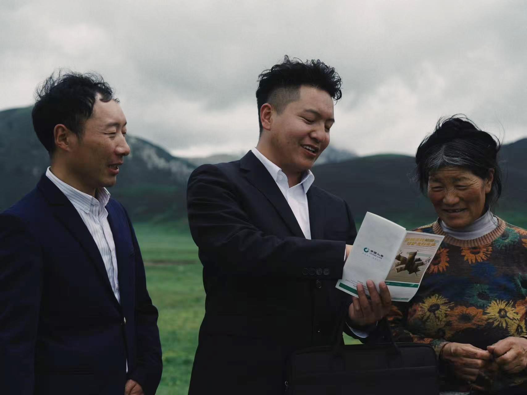 图:工作人员走到田间地头为农牧民介绍保险产品