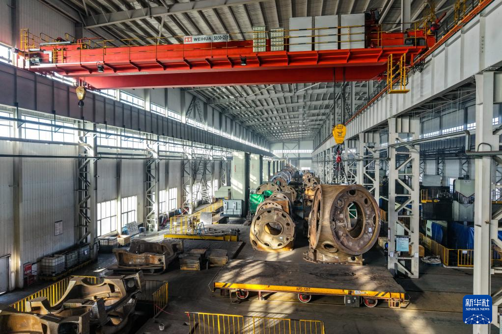 11月20日，在甘肃省酒泉经济技术开发区的日月重工（甘肃）有限公司机加车间，工作人员操作起重机转运风机轮毂（无人机照片）。