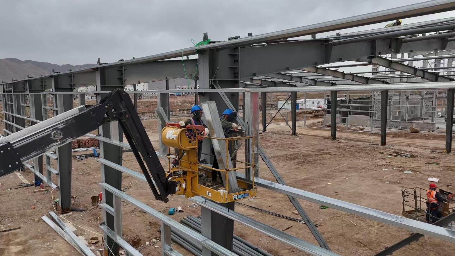 △甘肃郴金磊鑫环保科技有限公司20万吨/年危废处置中心生产线建设项目现场，工人们在钢结构之间进行焊接工作。（资料图）