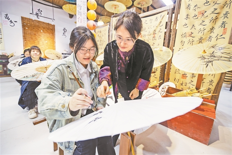 11月14日,位于婺源县思口镇前坦村的矛文女元婺源非遗体验中心,程卫华在指导游客画伞。