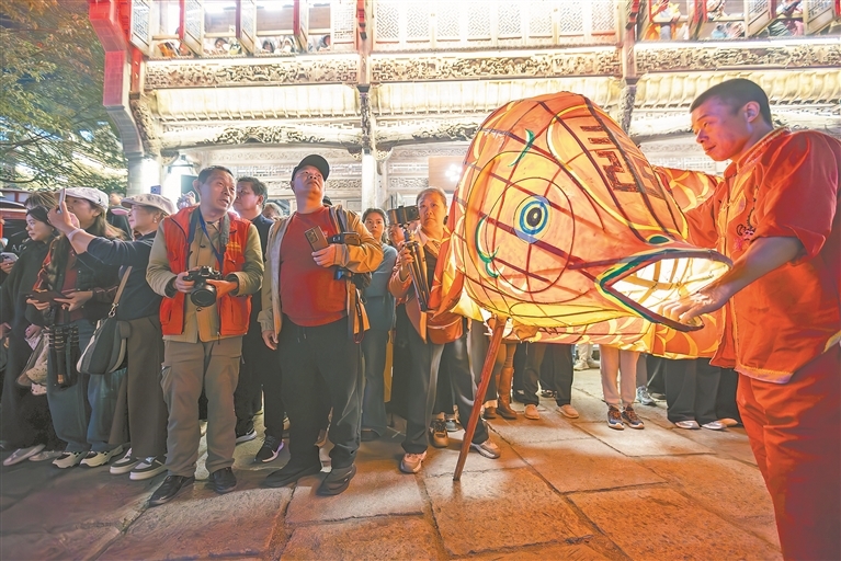 11月16日,婺源县弦高古城,江志红带着游客一边欣赏精彩的民俗表演,一边交流指导具体的拍摄方法。