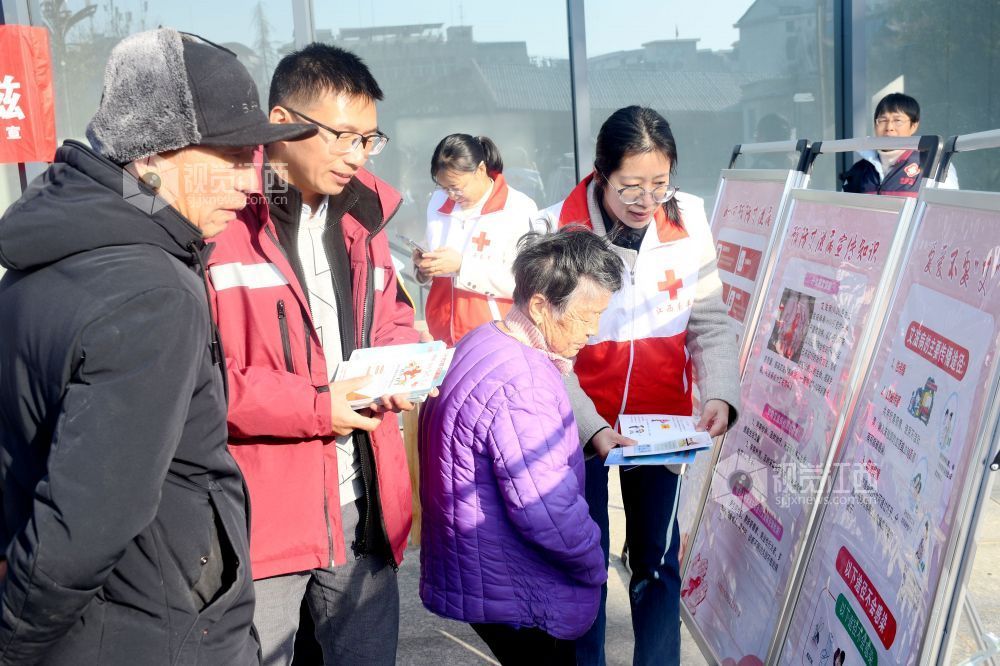图为县红十字志愿者利用防艾宣传展板向社区居民宣传防艾知识。