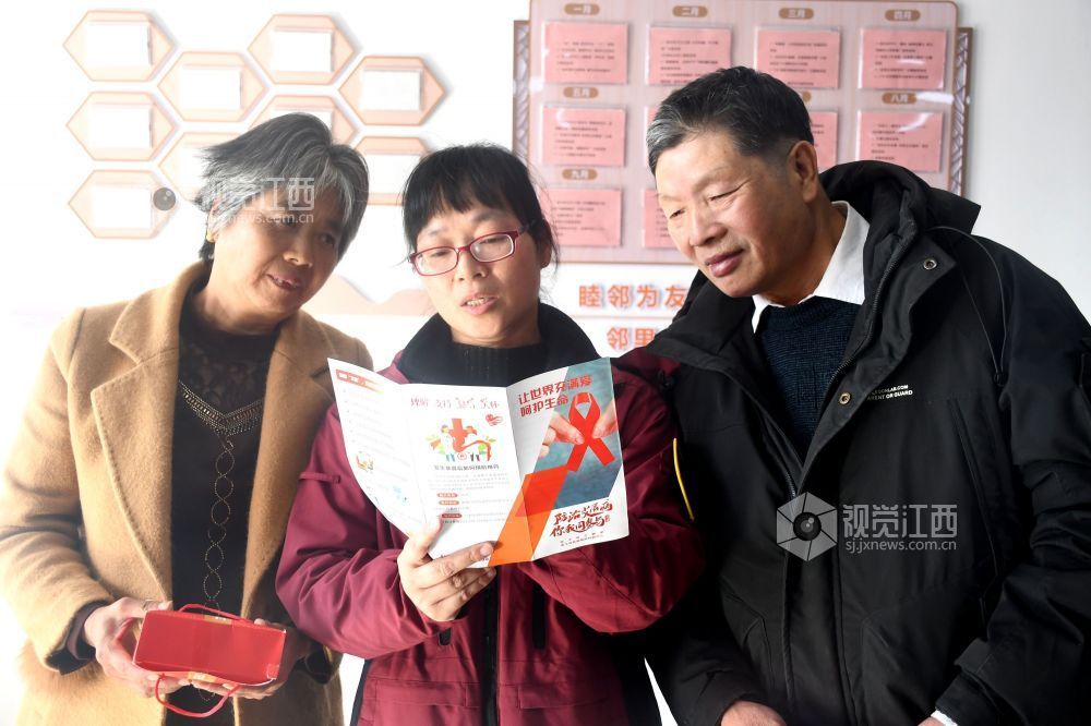 图为县疾控中心的工作人员利用防艾宣传资料为社区居民宣传防艾知识。