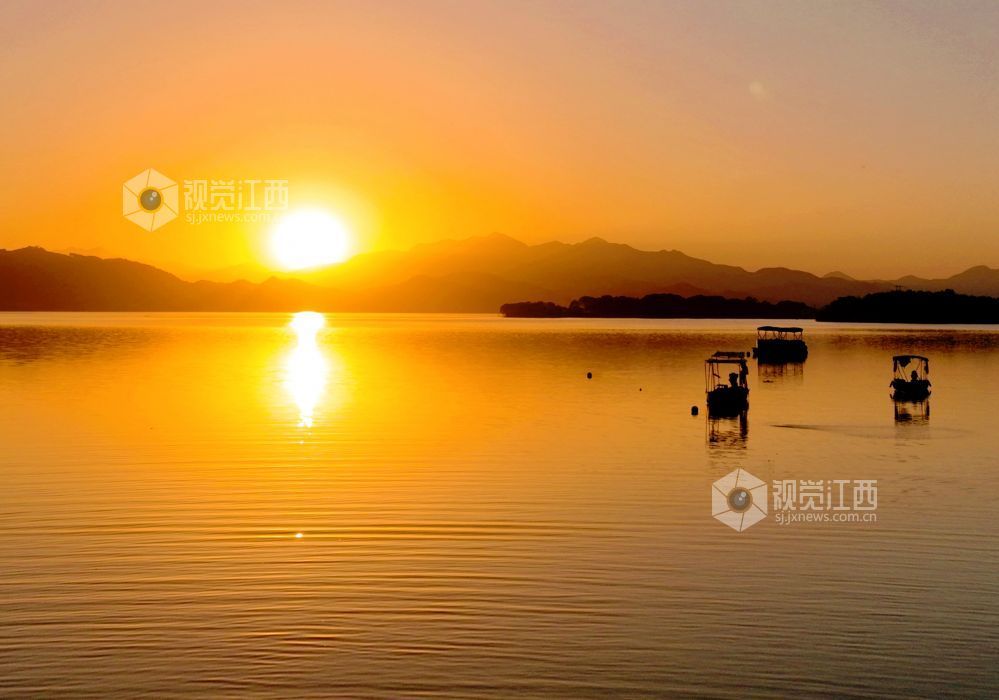 2025年11月26日，江西省分宜县钤阳湖在夕阳余晖的映照下，荡起层层涟漪，与远山丛林、湖中小船交相辉映，如诗如画，美不胜收。