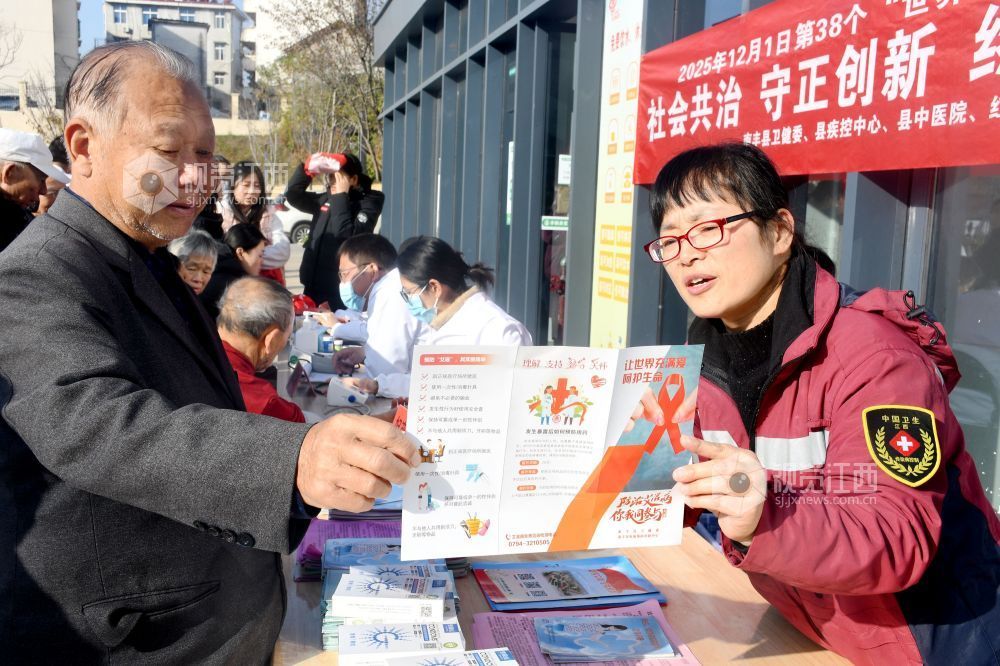图为县疾控中心的工作人员利用防艾宣传资料为社区居民宣传防艾知识。
