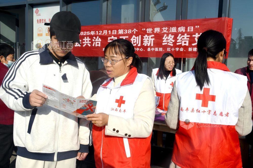 图为县红十字志愿者利用防艾宣传资料为社区居民宣传防艾知识。