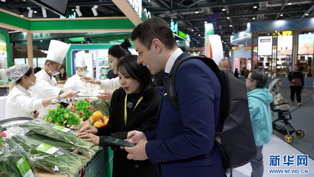 在中国绿色食品博览会展区，意大利参观者莫睿安正在扫码查看一份韭菜的溯源信息。新华网 发